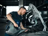Ames Volkswagen monteur giet vloeistof in de motorkap