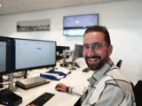 ICT beheerder lachend achter computer