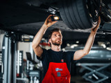 Ames monteur onder een auto met een zaklamp