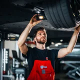 Ames monteur onder een auto met een zaklamp