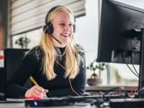 Telefoniste vrouw achter computer lachend met headset