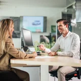 Man en vrouw in overleg bij een tafel in Ames Skoda showroom