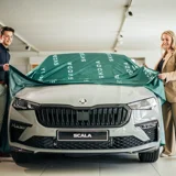 Man en vrouw halen een doek van een auto af