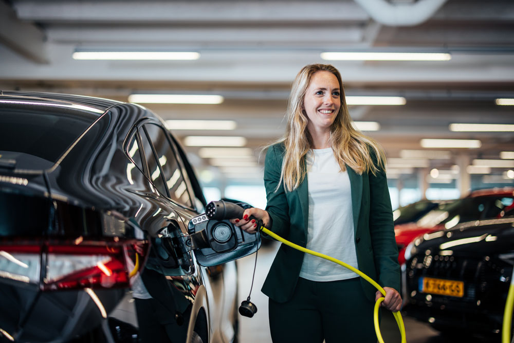 vrouw stopt een laadkabel in een auto