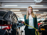 vrouw stopt een laadkabel in een auto