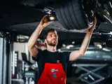Audi monteur bezig onder de auto bij de band
