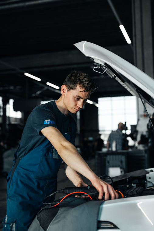 Ames volkswagen monteur bezig met kabels onder de motorkap